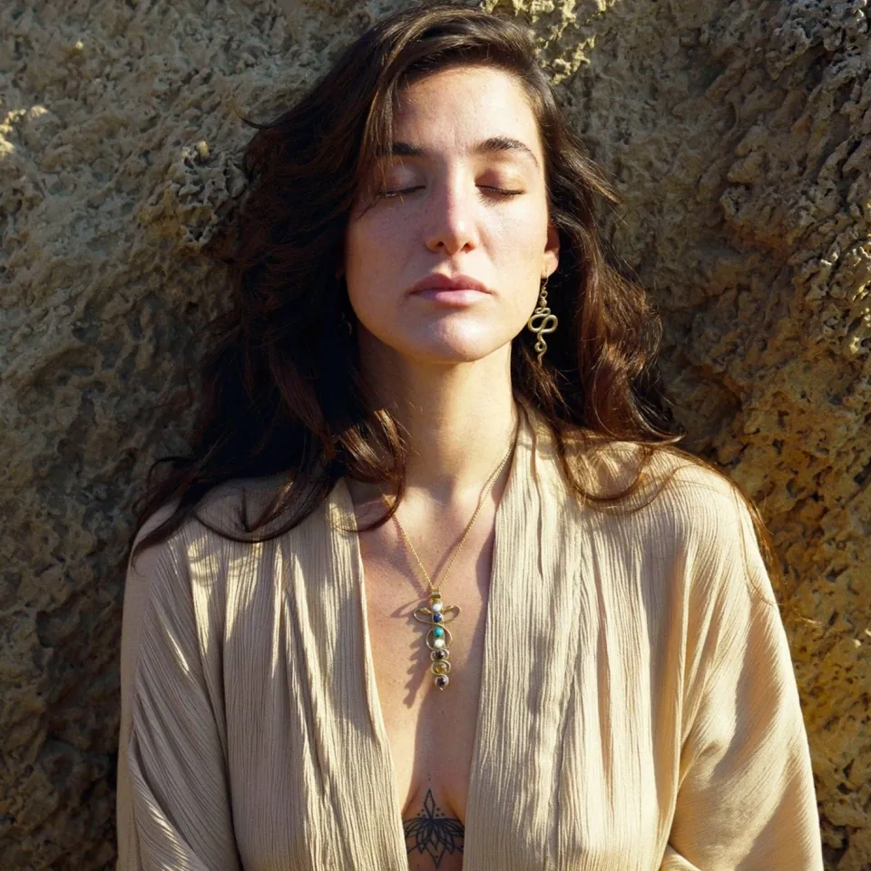 Woman wearing a gold seven-chakra necklace by Daya Jewelry